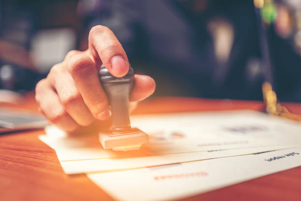 Close-up hand stamping of businessman for signing approval on documents , business concept Close-up hand stamping of businessman for signing approval on documents , business concept Licensing and Permits stock pictures, royalty-free photos & images