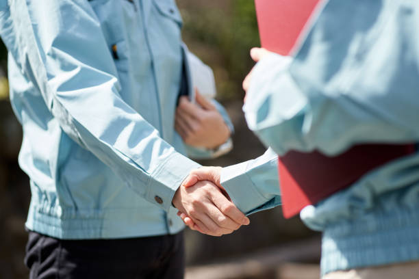 Construction worker shaking hands in front of the building Construction worker shaking hands in front of the building hiring construction employees stock pictures, royalty-free photos & images