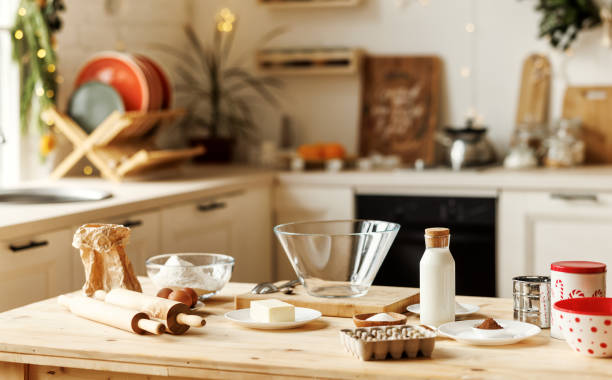 Holiday baking. Ingredients for traditional Christmas cookies on kitchen countertop Holiday baking. Ingredients for traditional Christmas cookies on kitchen countertop, table with flour, rolling pin, milk, eggs, cocoa powder and butter for preparing xmas sweets or gingerbreads Baking  ingredients stock pictures, royalty-free photos & images