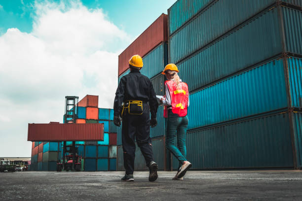 Industrial worker works with co-worker at overseas shipping container yard . Logistics supply chain management and international goods export concept . Industrial worker works with co-worker at overseas shipping container yard . Logistics supply chain management and international goods export concept . Equipment and Suppliers in construction  stock pictures, royalty-free photos & images