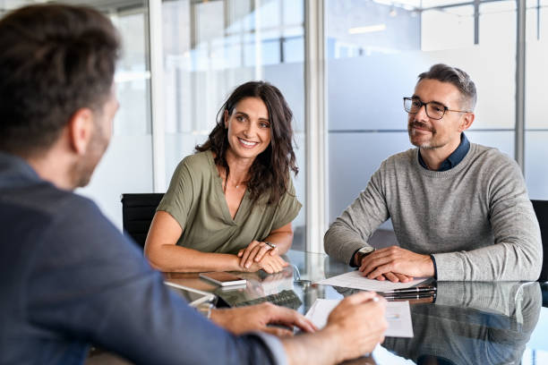 Mature couple meeting financial advisor for investment Smiling mature couple meeting with bank manager for investment. Beautiful mid adult woman with husband listening to businessman during meeting in conference room in modern office. Happy middle aged couple meeting loan advisor to buy a new home. Business Ownership stock pictures, royalty-free photos & images