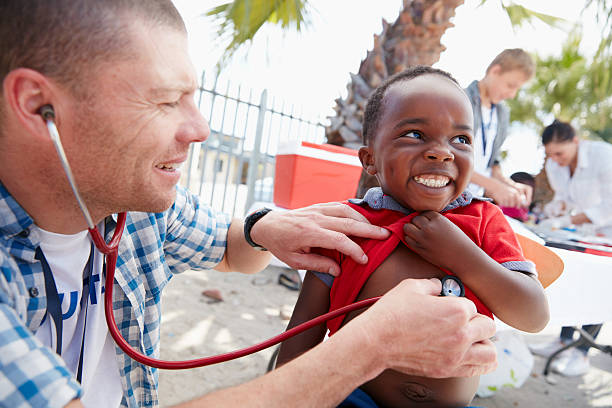 That tickles! Shot of a volunteer doctor giving checkups to underprivileged kids organizations that help patients stock pictures, royalty-free photos & images