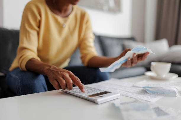 Close up of a mid adult woman checking her energy bills at home, sitting in her living room. She has a worried expression Close up of a mid adult woman checking her energy bills at home, sitting in her living room. She has a worried expression Cheque stock pictures, royalty-free photos & images